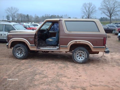 1990 Ford F-150 - This 1980s Ford Bronco is parked outdoors with its door open, showing the interior.