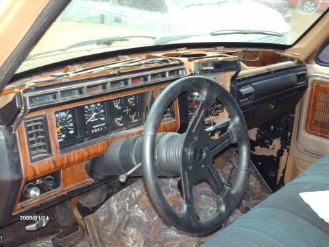1990 Ford F-150 - The interior of a truck shows a woodgrain dashboard and an aftermarket steering wheel, suggesting an older model year.