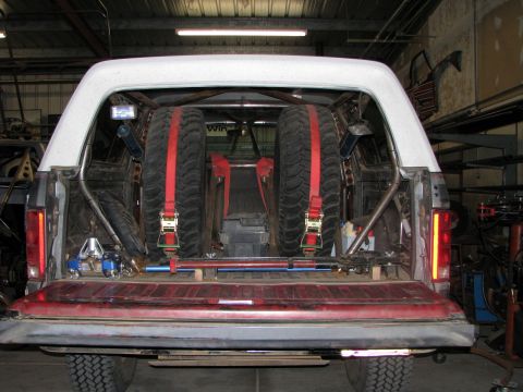 1980 Ford Bronco - Rear view of a modified 1980 Ford Bronco, showing its cargo area equipped with spare tires and roll cage.