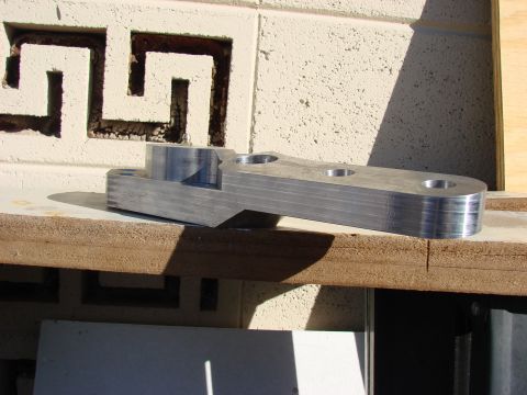1979 Ford Bronco - A machined metal component with several drilled holes is shown on a wooden surface.