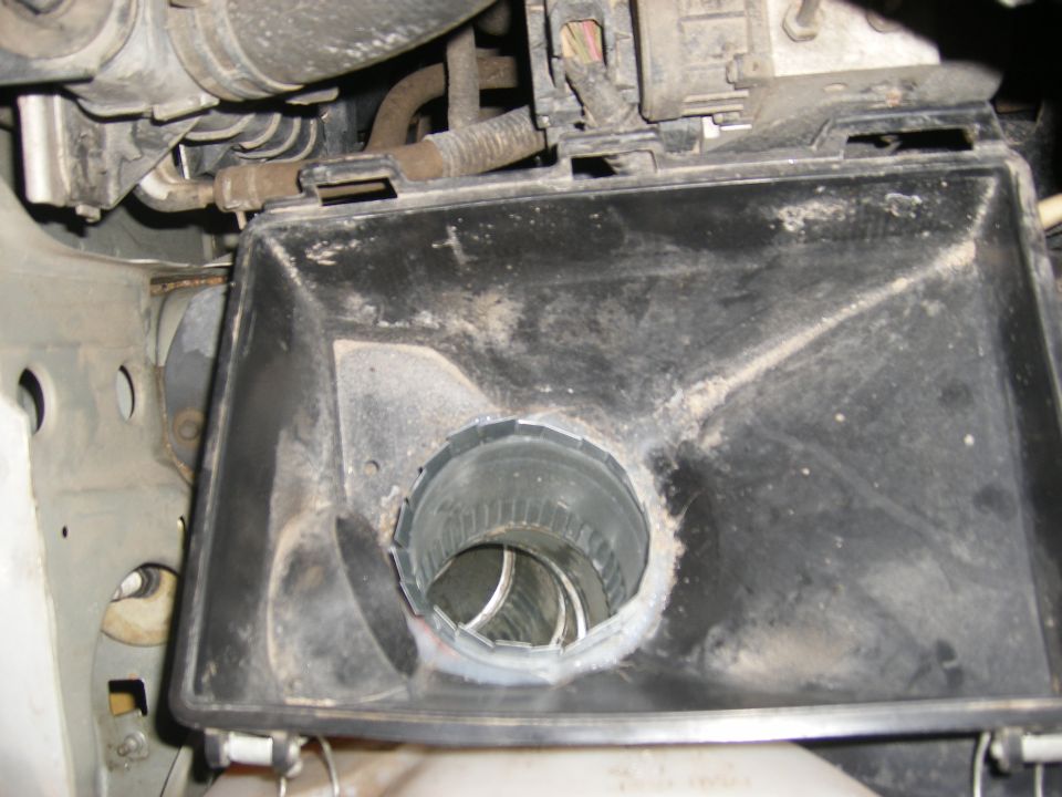 Black plastic air intake housing with a metal duct opening, showing dust and grime