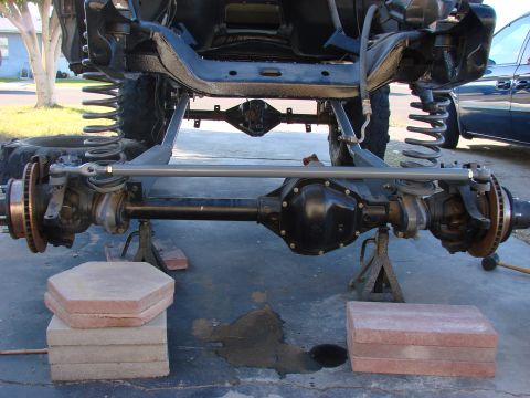 1979 Ford Bronco - Front axle and suspension parts are visible, supported by jack stands during maintenance.
