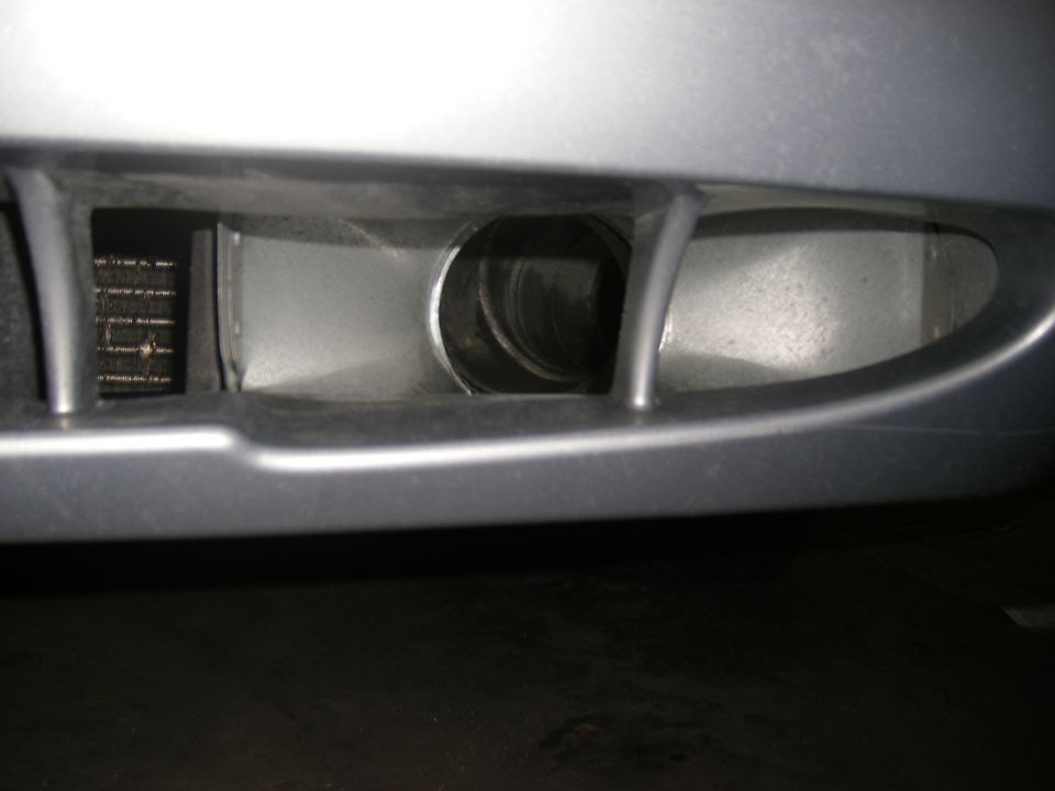Close-up of a car's front bumper with a circular opening and a grille behind it