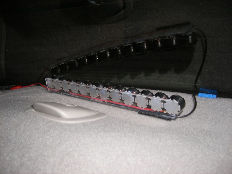 Car interior with a row of circular components wired together, mounted under a seat