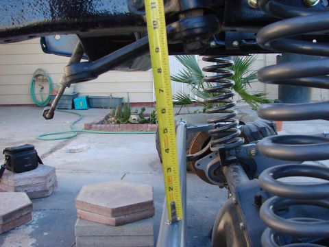 1979 Ford Bronco - Close-up of a vehicle's front suspension components, with a yellow measuring tape indicating height.