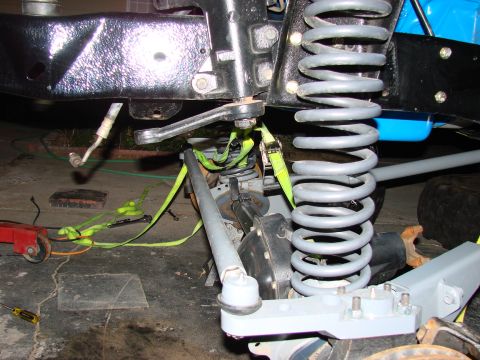 1979 Ford Bronco - Detail of vehicle suspension components, including a large coil spring and tie rod assembly.