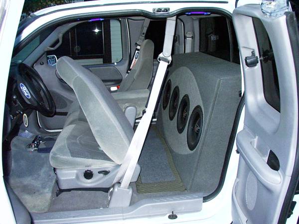 Extended-cab pickup interior with four subwoofers in a carpeted enclosure behind the front seats