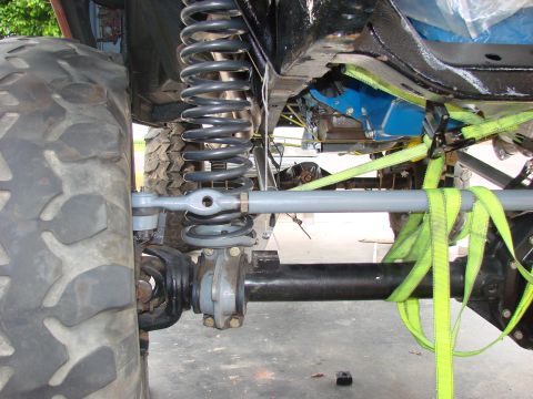 1979 Ford Bronco - Underneath view of a vehicle's front suspension system, showing the tire, spring, and steering components.