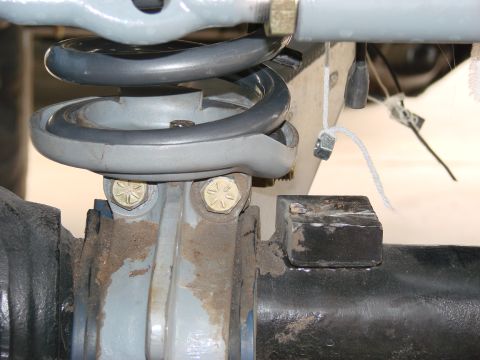 1979 Ford Bronco - This image shows a close-up view of a vehicle's suspension system, focusing on the coil spring and axle components.