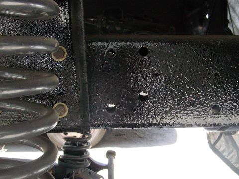 1979 Ford Bronco - Undercarriage view showing frame and suspension components, including a large coil spring.