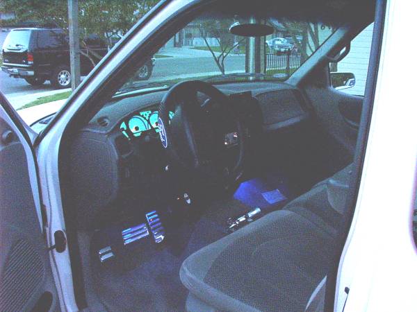 Pickup driver interior with teal-lit gauges, blue footwell neon and billet pedal covers
