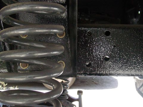 1979 Ford Bronco - Vehicle suspension component, likely a coil spring and frame section, viewed from below.