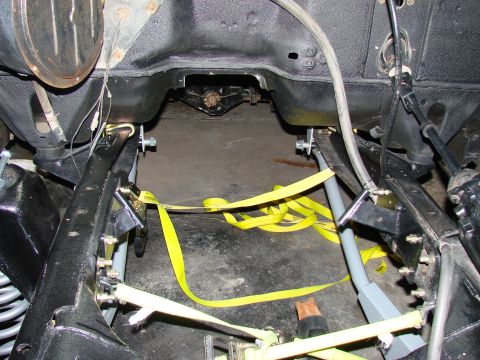 1979 Ford Bronco - Underneath view of a 1979 Ford Bronco's engine bay, showing frame and suspension with securing straps.