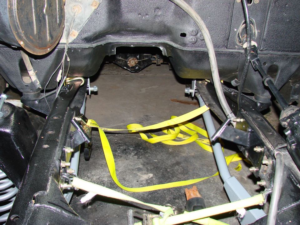 1979 Ford Bronco frame with yellow straps, engine bay visible, suspension components