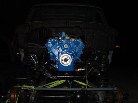 1979 Ford Bronco - The engine bay is open, showing a freshly painted blue engine being installed in the vehicle.