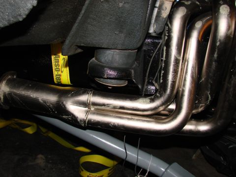 1979 Ford Bronco - Exhaust headers and suspension parts are visible, with yellow tie-down straps in place.
