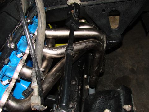 1979 Ford Bronco - The engine bay shows a blue-painted block, custom exhaust headers, and part of the steering column.