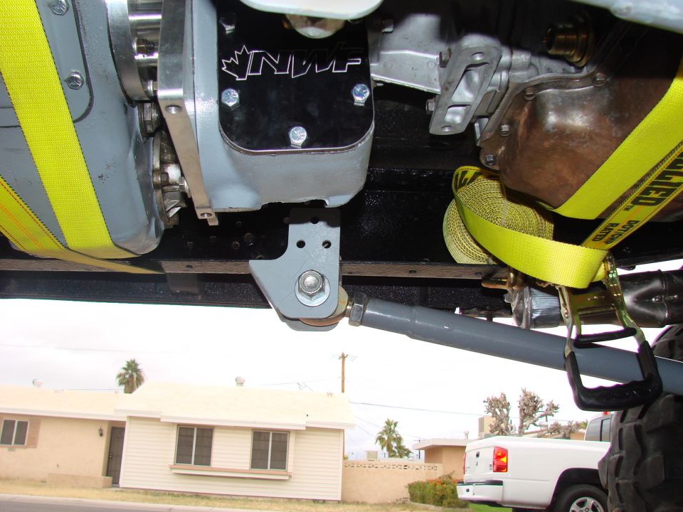 Underbody view of a transfer case with NWF plate, gray brackets and yellow straps