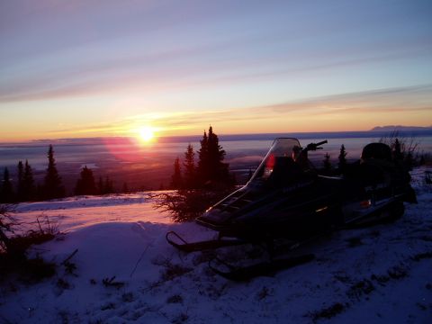 2000 Ford E350 - A snowmobile sits on a snow-covered ridge overlooking a valley at dawn.