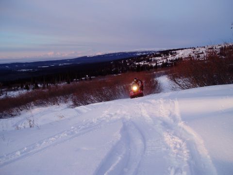 2000 Ford E350 - Snowmobile rider navigates a snowy hill during twilight, leaving tracks in the fresh snow.