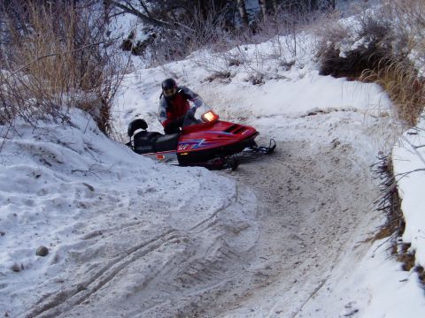 2000 Ford E350 - A red snowmobile navigates a snow-covered trail with a rider.