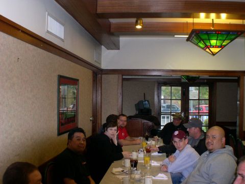 2007 Toyota FJ Cruiser - A group of people are seated at a table inside a restaurant, with a framed picture on the wall reflecting a vehicle.
