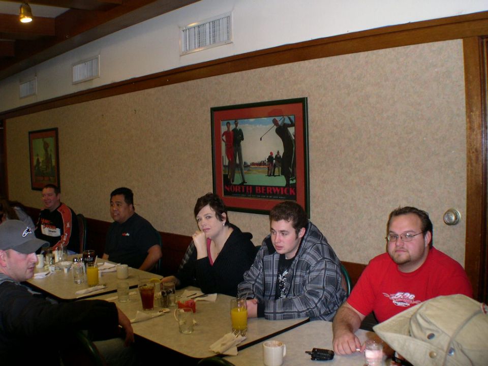 People seated at tables in a restaurant, with a golf-themed picture on the wall