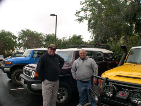 2007 Toyota FJ Cruiser - Two men stand with three Toyota FJ Cruisers, a blue, a maroon, and a yellow one, parked in an outdoor lot.