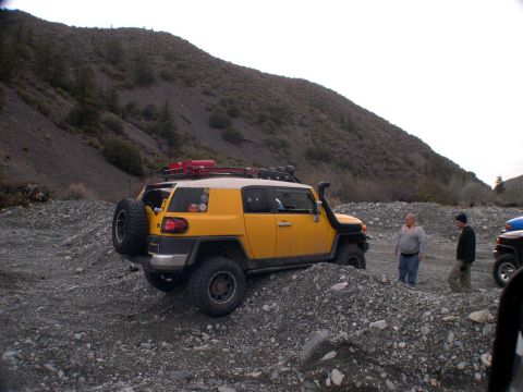2007 Toyota FJ Cruiser - A yellow 2007 Toyota FJ Cruiser navigates a rocky off-road path with two onlookers.