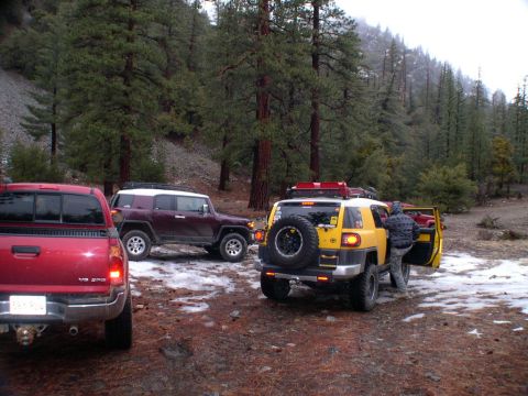 2007 Toyota FJ Cruiser - Three off-road vehicles are parked in a wooded area with scattered snow on the ground.