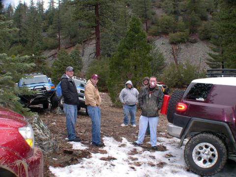 2007 Toyota FJ Cruiser - A group of people stand around several off-road vehicles in a snowy, wooded area.