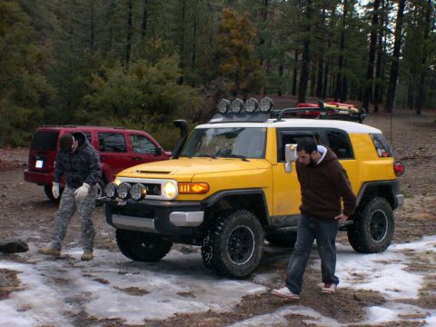 2007 Toyota FJ Cruiser - A yellow 2007 Toyota FJ Cruiser is parked in a snowy, wooded area with a red SUV behind it.