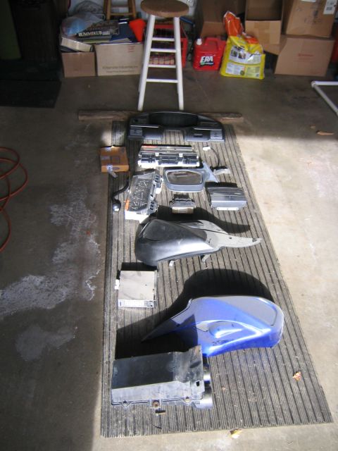 1994 Ford Bronco - Various motorcycle components are organized on a mat in a garage setting.