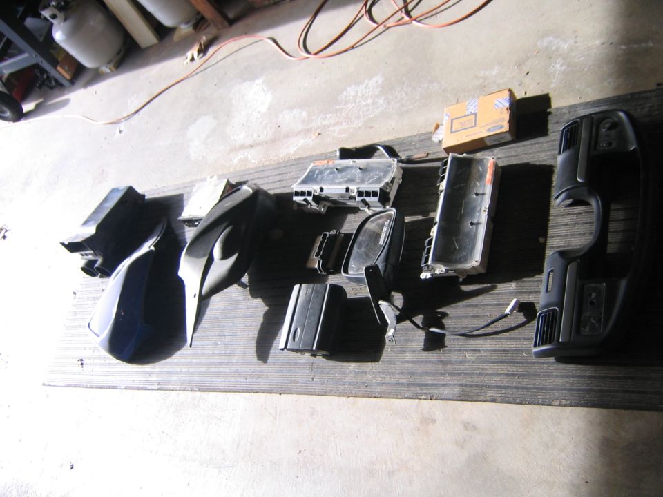 Assortment of dark-colored vehicle interior parts laid out on a wooden surface