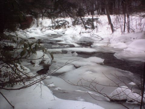 1966 Land Rover Discovery - A frozen stream flows through a snow-covered landscape with bare trees in the background.