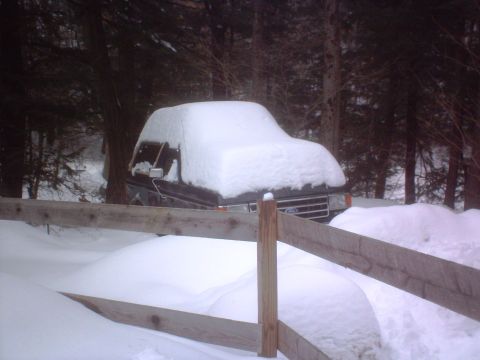 1966 Land Rover Discovery - A Ford truck is partially buried in snow, with only the front grille and part of the hood visible.