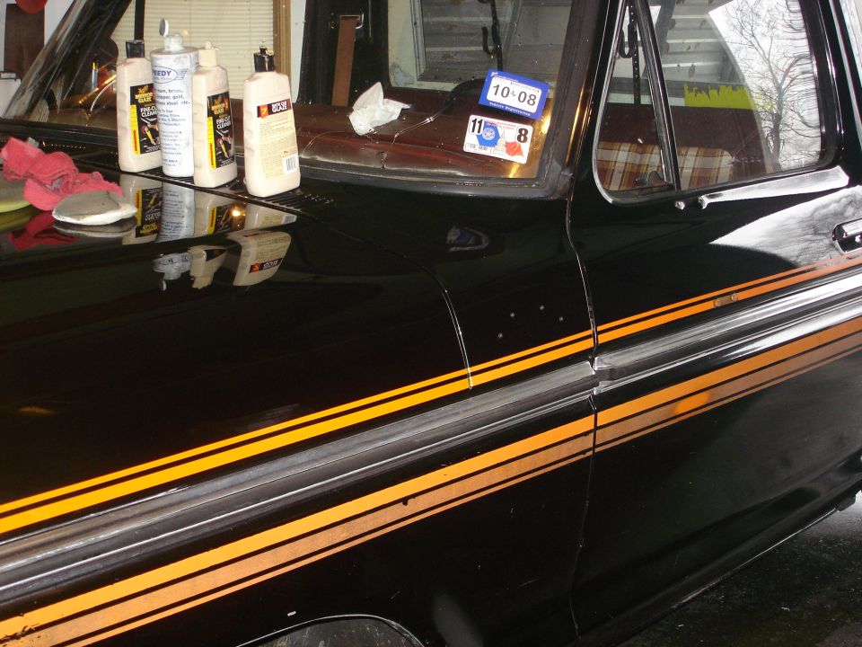 Black 1979 Ford F-150 with orange and grey side pinstripes, showing a detailer's supplies on the hood