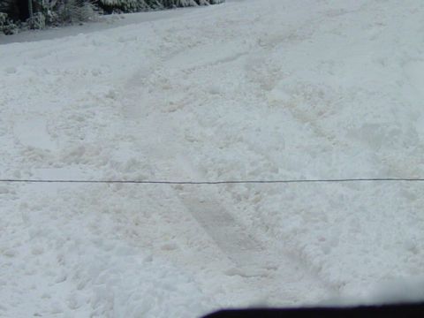 1986 Ford Bronco - A snowy road shows tire tracks, suggesting recent vehicle passage through winter conditions.