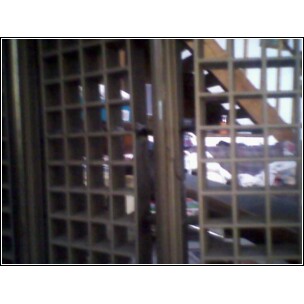 1972 Ford Ranchero - A view through metal grating and wooden structures, possibly in a storage or workshop area.