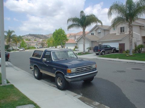 1986 Ford Bronco - A blue 1987 Ford Bronco is parked on the side of a residential street.