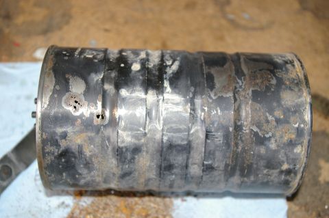 1986 Ford Bronco - This is a close-up view of a heavily corroded exhaust muffler, showing signs of wear and damage.