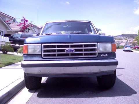1986 Ford Bronco - This 1986 Ford Bronco features a distinctive chrome grille and 4x4 badging, seen from a straight-on front view.