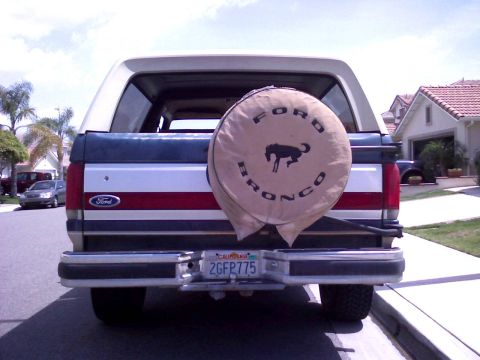 1986 Ford Bronco - The rear of a Ford Bronco is visible, a spare tire cover with the model name and a horse emblem.