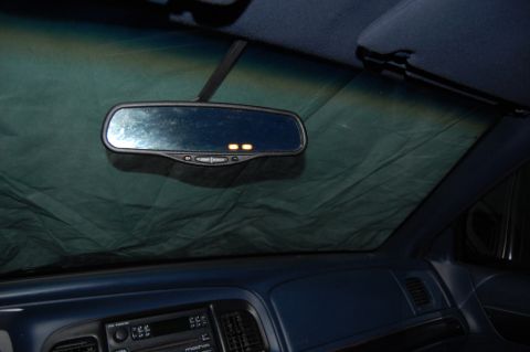 1985 Mercury Grand Marquis - Interior view of a car's dashboard and rearview mirror, partially obscured by a sunshade.