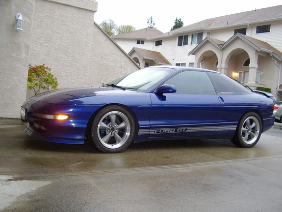 Blue Ford Probe with silver racing stripes on the side, parked on a wet driveway