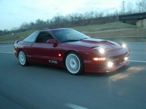 1994 Ford Probe - This red 1994 Ford Probe GTS is captured in motion on a highway as dusk approaches.