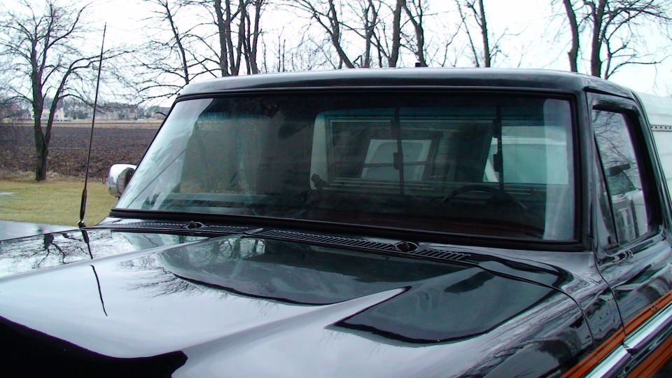 Black 1973 Ford F-Series truck, front passenger side, with a chrome antenna and a partial view of the hood