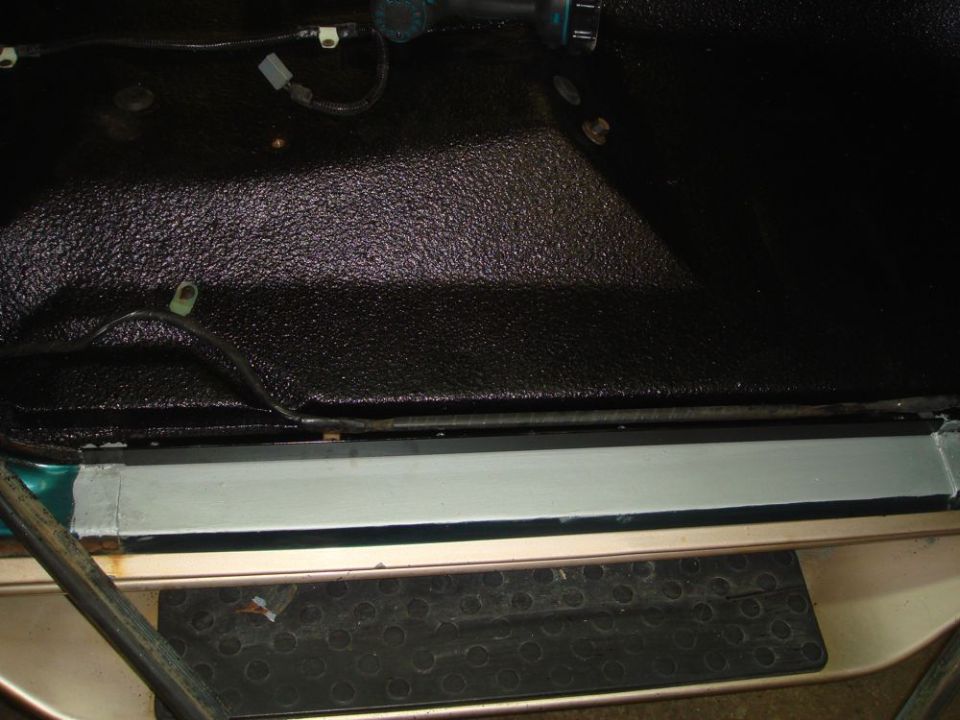 close-up of textured black floor liner and metal trim inside a vehicle