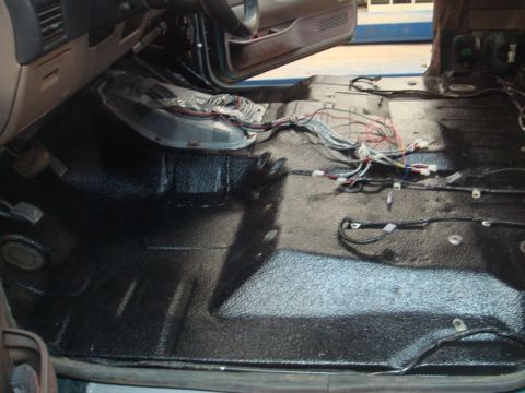 1996 Ford Bronco - The interior of a vehicle shows exposed wiring and a black textured floor after carpet removal.