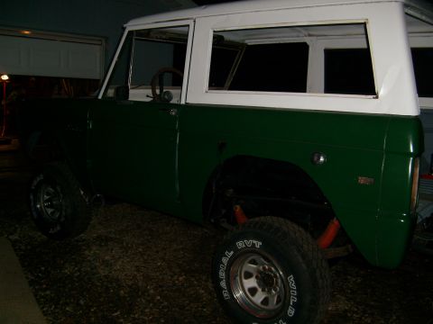 1974 Ford Bronco - A green and white 1974 Ford Bronco is viewed from the rear quarter angle, highlighting its off-road capabilities.